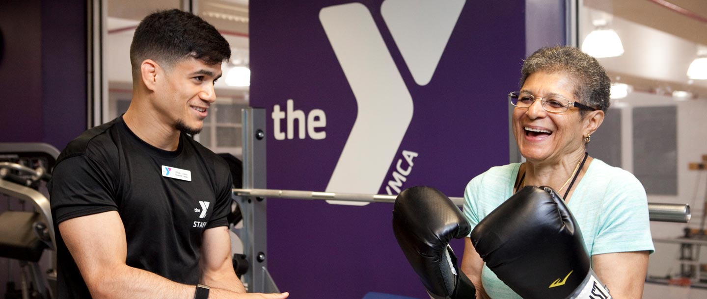 A member with boxing gloves works with a YMCA personal trainer.