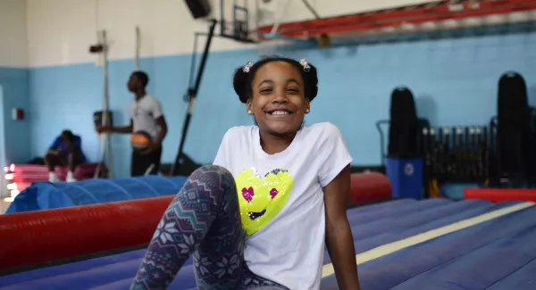 girl sitting on gym mats