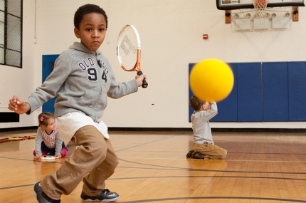 Kid learns tennis during youth sports class at the Harlem YMCA