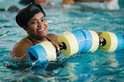 Woman smiling in Bronx YMCA indoor pool during water aerobics class