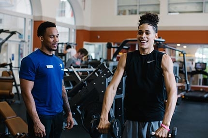 Teen lifts weights with personal trainer at Ridgewood YMCA strength training center in Queens
