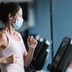 A YMCA member works out on a treadmill in a mask at the Y.