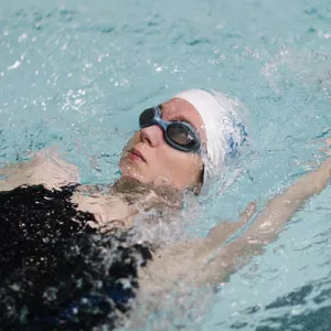 A woman swims the backstroke in a YMCA pool.