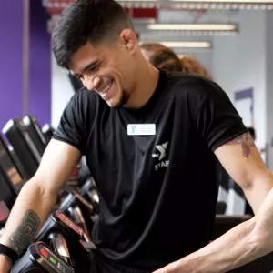 A personal trainer works with a YMCA member in the gym.