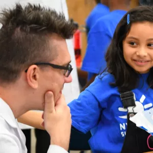 A girl shows a camp instructor her science project at the Dodge YMCA summer day camp.