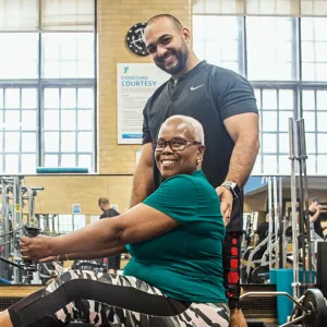 A woman works out with weights and a personal trainer at the Y.