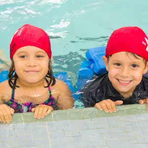 Campers swimming on side of YMCA indoor pool during summer camp