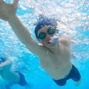 Boy swims laps at McBurney YMCA indoor pool with bubbles coming out of his face