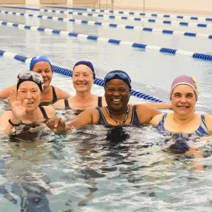 Group of women smiling at YMCA indoor pool water fitness class