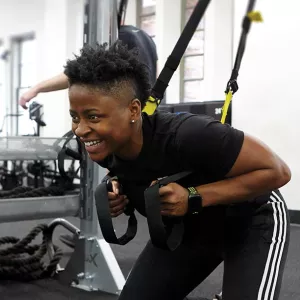 YMCA instructor demonstrates how to squat with TRX equipment during fitness class at YMCA gym