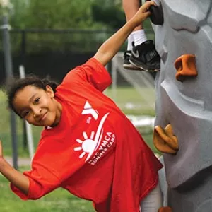 Summer camper climbing rock wall