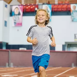 Boy running on track at Park Slope Armory YMCA kids run class in Brooklyn